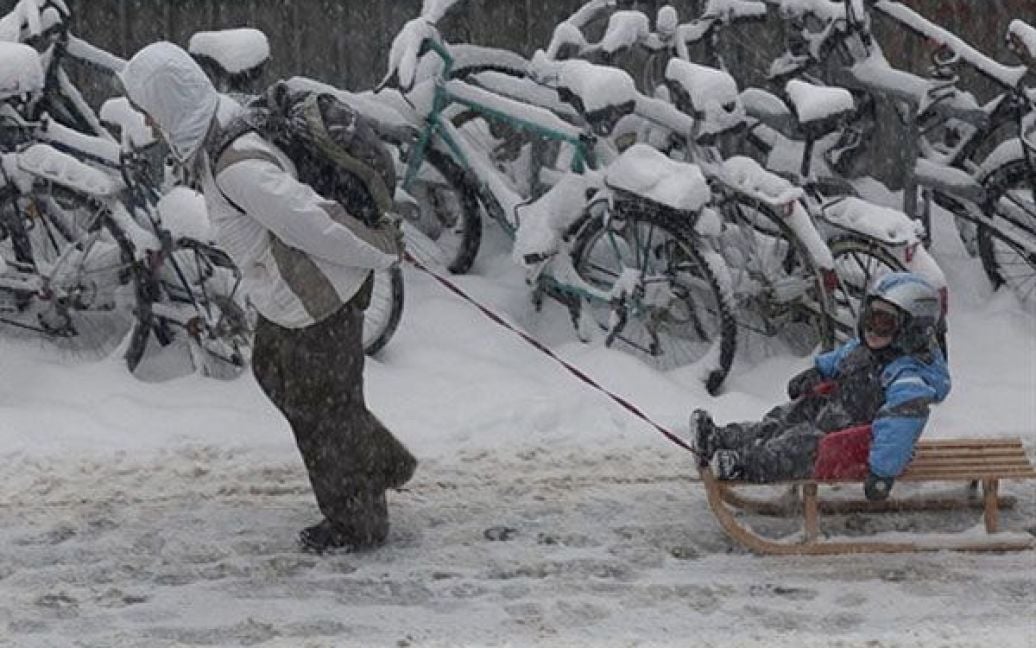 Швейцарія, Берн. Жінка везе свою дитину на санчатах під час снігопаду в Берні.  на 1 грудня 2010 року. Сильні снігопади змусили закритися деякі завантажені аеропорти Європи, викликати хаос на дорогах і залізницях. / © AFP