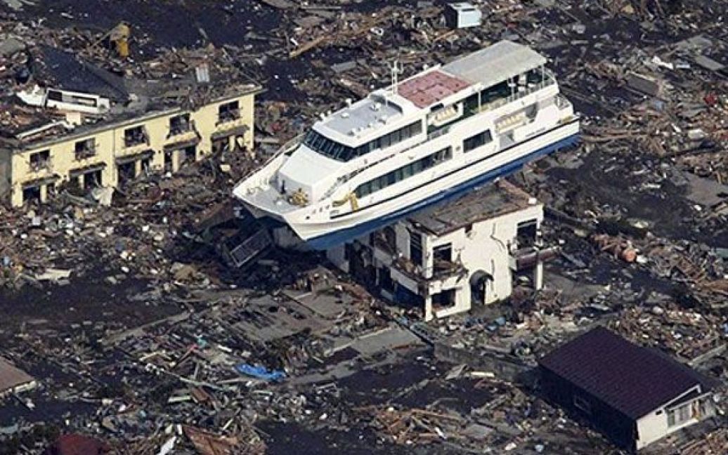 Японія, Отсучі. Прогулянковий катер потрапив на дах зруйнованої під час цунамі будівлі на фоні моря сміття у місті Отсучі, префектура Івате. / © AFP