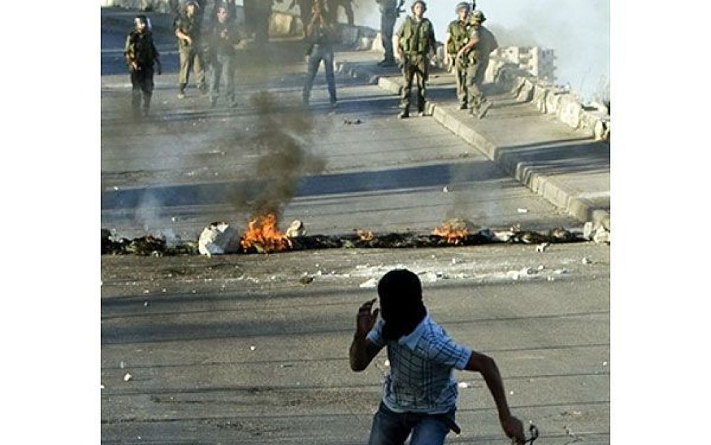 Єрусалим. Палестинський мітингувальник у масці тікає від ізраїльських солдатів після того, як він кидав у них камінням. Нові зіткнення між палестинцями та ізраїльськими поліцейськими стались на околиці Східного Єрусалиму / © AFP