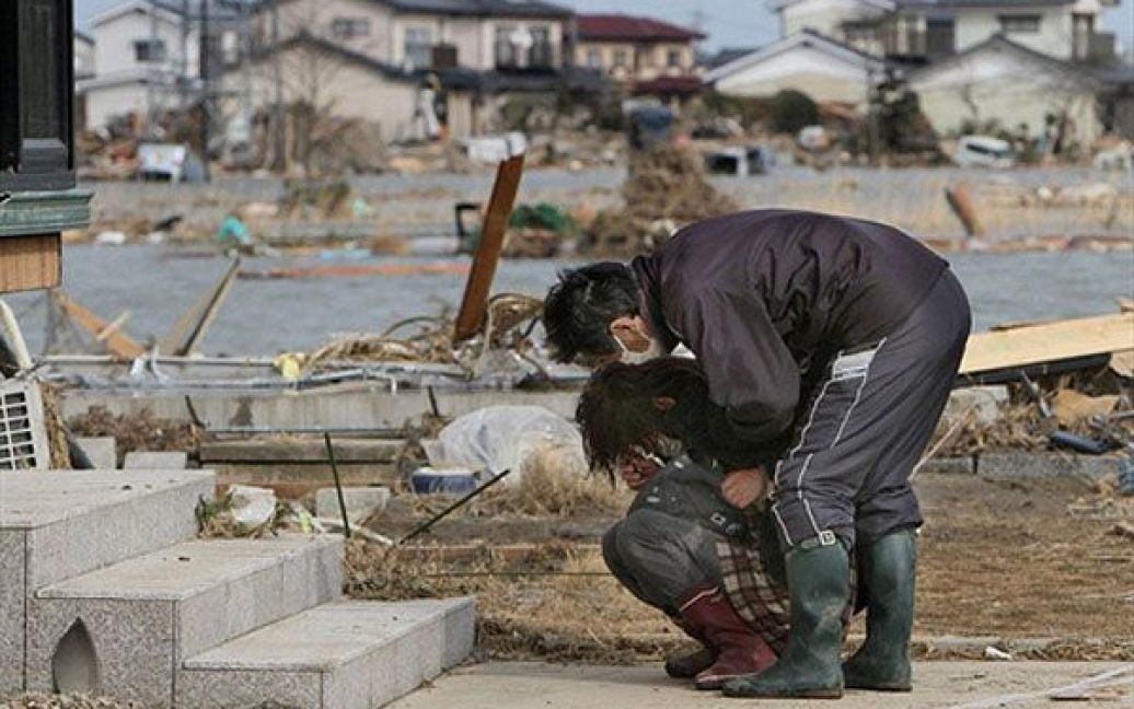 Японія, Ватарі. Чоловік заспокоює жінку, яка плаче перед своїм пошкодженим будинком у місті Ватарі, префектура Міягі. Руйнівні землетруси та хвилі цунамі призвели до загибелі тисяч людей у Японії . / © AFP