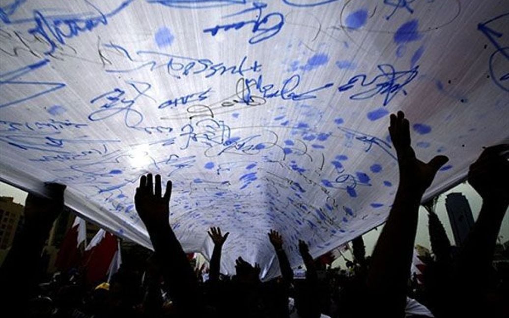 Бахрейн, Манама. Бахрейнські шиїтські антиурядові демонстранти розгорнули гігантський національний прапор зі своїми підписами на мітингу в пам&#039;ять про сімох осіб, які були вбиті поліцейськими під час розгону демонстрацій на Перлиновій площі у Манамі. / © AFP