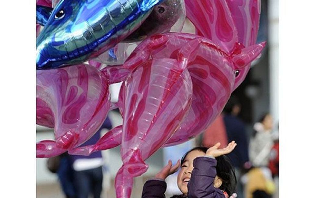Японія, Йокогама. Дівчина грає з повітряною кулькою у формі дельфіна на площі у Йокогамі. / © AFP