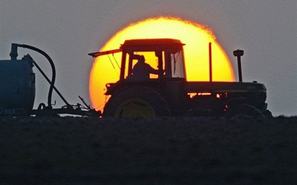 Німеччина, Фельдкірхен. Фермер веде свій трактор полем на сході сонця. / © AFP