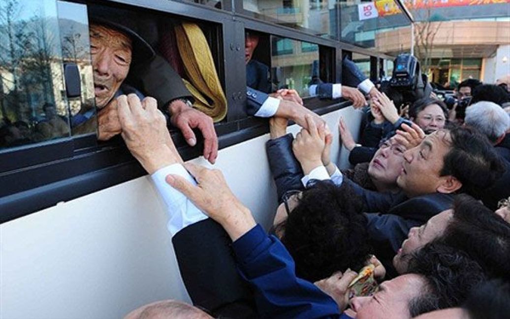 КНДР, гора Кимган. Північнокорейці (в автобусі) хапають за руки своїх південнокорейських родичів під час прощання після триденної зустрічі розділених сімей, яку провели на горі Кимган у Північній Кореї, неподалік від кордону. Сотні жителів Південної Кореї отримали можливість зустрітися зі своїми північнокорейськими родичами, з якими їх розділили після закінчення Корейської війни. / © AFP