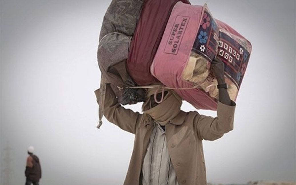 Туніс. Суданські біженці, які втекли з Лівії, несуть на голові свої валізи. / © AFP