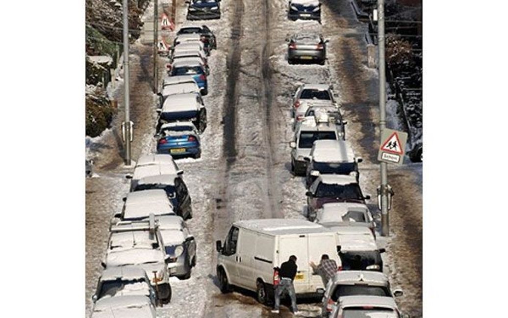Великобританія, Глазго. Люди виштовхують автобус на дорогу, вкриту снігом і кригою, у Глазго, Шотландія. Сотні автомобілів у Шотландії опинились у сніговій пастці після сильного снігопаду. / © AFP