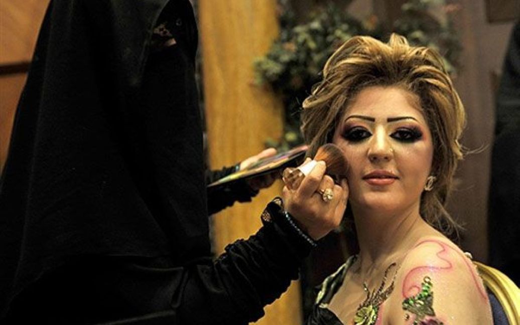 Саудівська Аравія, Джидда. Саудівська жінка робить макіяж моделі під час конкурсу з краси і стилю, який відбувся в рамках виставки "Косметик Експо 2010". Ця чотириденна виставка стала першою подібною виставкою в Саудівській Аравії. / © AFP