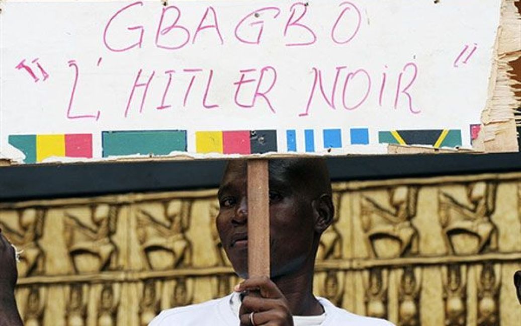 Кот-д&#039;Івуар, Абіджан. Прихильник визнаного світом лідера Кот-д&#039;Івуара Алассана Уаттара тримає плакат із написом "Гбагбо: чорний Гітлер" під час демонстрації у Абіджані. Троє західноафриканських лідерів провели зустріч із президентом Нігерії і закликали Гбагбо піти у відставку. / © AFP