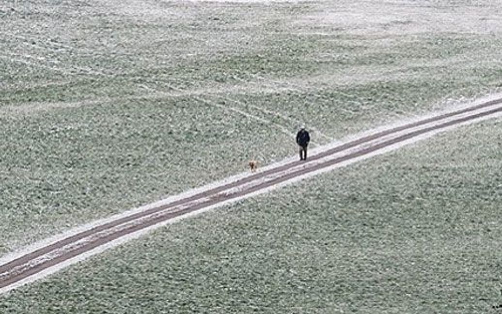 Німеччина, Санкт-Енглмар. Чоловік і його собака йдуть дорогою, вкритою снігом, поблизу міста Санкт-Енглмар на півдні Німеччини. / © AFP