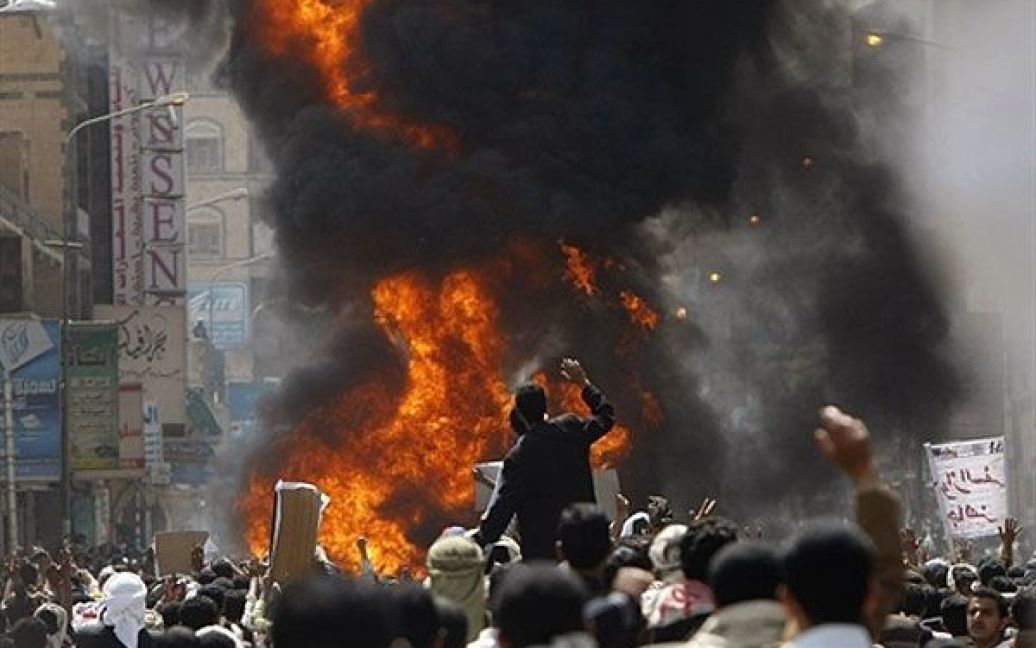 Ємен, Сана. Учасники антиурядової демонстрації спалюють автомобіль, який належить прихильнику уряду, під час акції протесту перед будівлею університету в Сані. Близько 1000 студентів провели другу ніч на площі "Аль-Хуррем" (площі Свободи) із вимогами повалення президента Ємену Алі Абдалли Салеха. / © AFP
