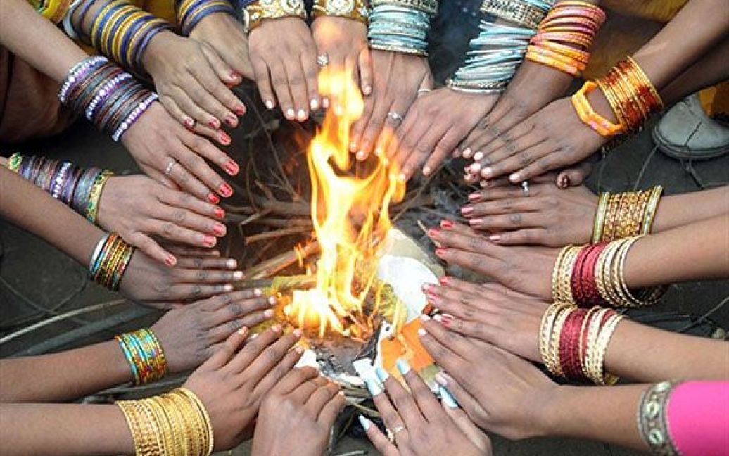 Індія, Амрітсар. Індійські дівчинки гріють руки на вогні перед виступом на святі у державній школі в Амрітсарі. Різке похолодання у Північній Індії вже призвело до десятків жертв. / © AFP