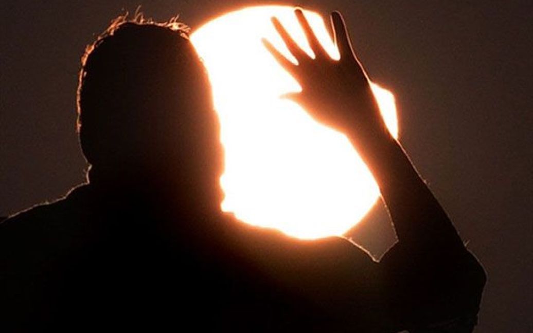 Пакистан, Лахор. Пакистанець піднімає руку, доки він дивиться на перше у 2011 році часткове сонячне затемнення у Лахорі. Під час першого часткового сонячного затемнення Сонце закрило на 30 відсотків. / © AFP