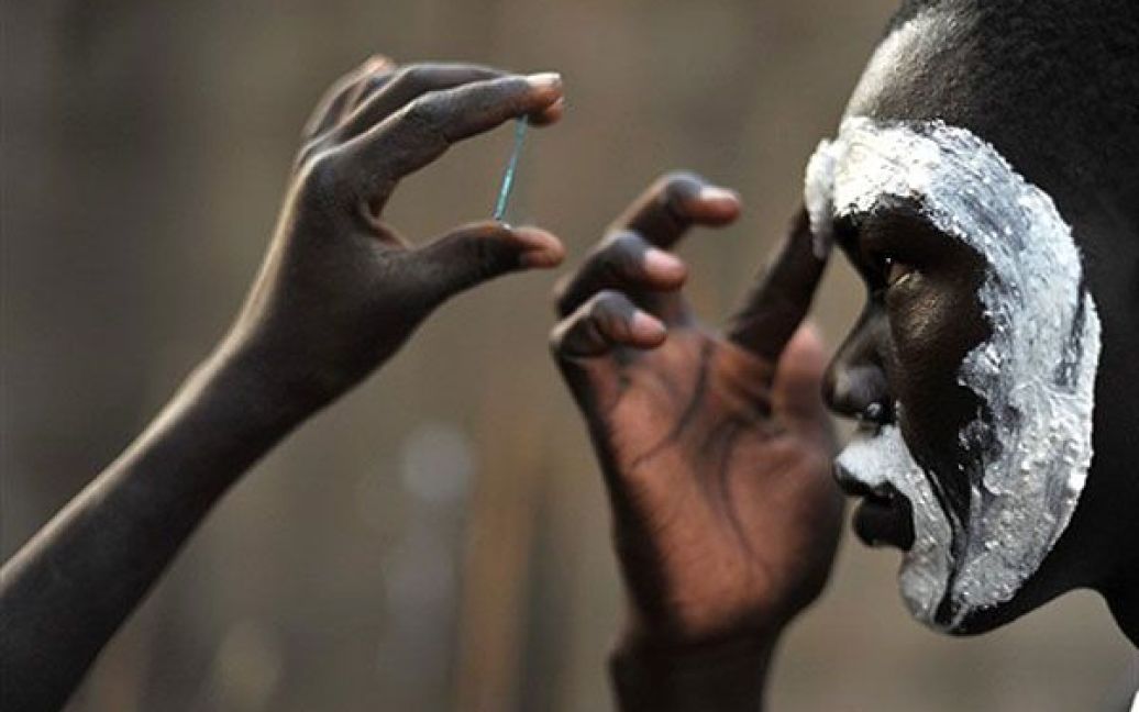 Судан, Джуба. Південносуданський юнак з національної танцювальної трупи розфарбовує обличчя змоченою крейдою перед виступом свого племені в Джубі. Судан відсвяткував завершення референдуму з питання незалежності, який тривав протягом тижня. / © AFP