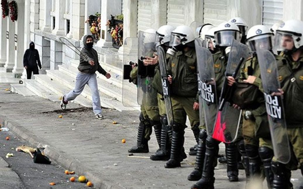Греція, Афіни. Молодь кидає каміння та речі у поліцейських під час акції протесту в центрі Афін. Студенти закидали камінням вікна банків і магазинів під час ходи до будівлі парламенту. / © AFP