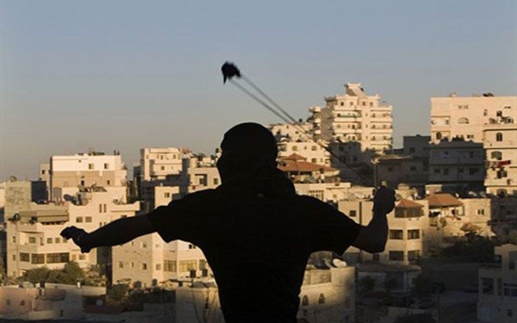 Єрусалим. Палестинський юнак у масці кидає камінь в ізраїльську прикордонну поліцію під час зіткнень у арабському районі Східного Єрусалиму Іссавія. / © AFP