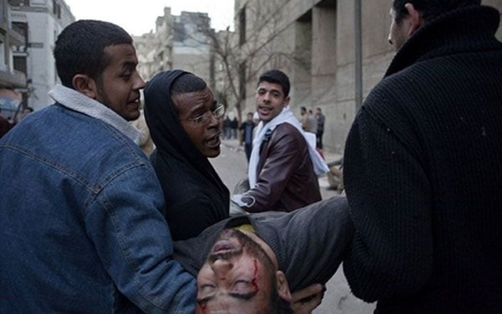 Єгипет, Каїр. Єгипетські демонстранти несуть свого товариша, який був поранений поліцейськими під час зіткнень поблизу центральної площі у Каїрі. Десятки людей отримали поранення, десятки були вбиті під час антиурядових протестів у центрі Каїра. / © AFP