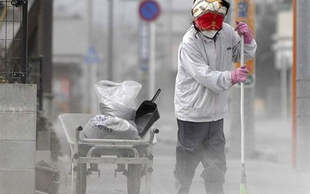 Японія, Міяконоджо. Жінка розчищає дорогу від вулканічного попелу. В результаті кількох вивержень вулкана Сінмоедаке у південній частині Японії, у повітря на тисячу метрів піднявся стовп попелу і диму. Хмара попелу викликала затримки із міжнародними авіаперевезеннями в Токіо. / © AFP