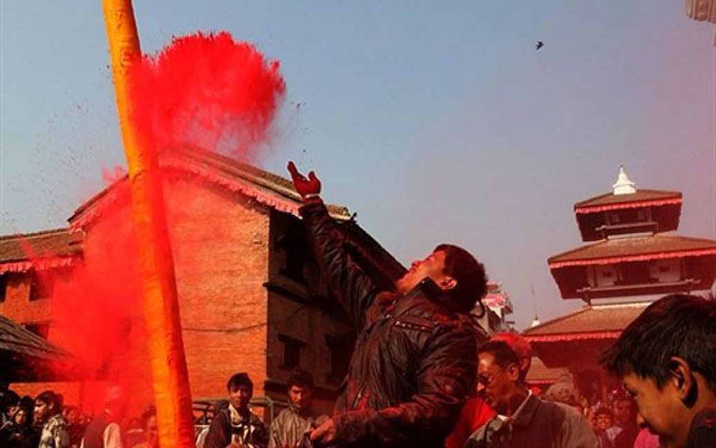 Непал, Катманду. Непалець кидає у повітря кольоровий порошок після церемонії встановлення традиційного бамбукового "Чира" під час першого дня святкування фестивалю квітів Холі на площі Дурбар в Катманду. / © AFP
