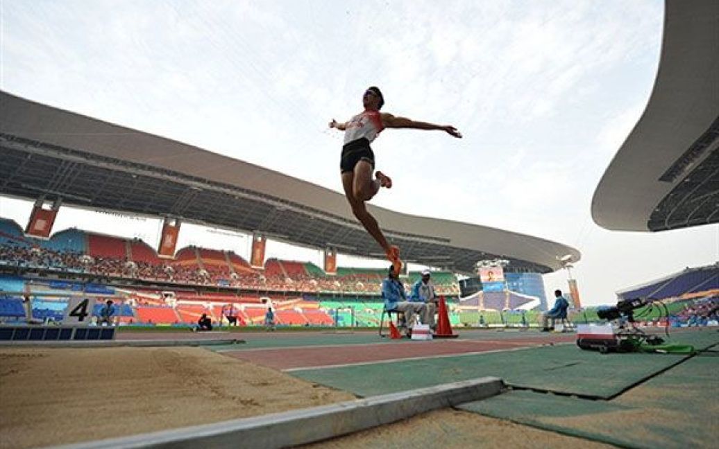 Китай, Гуанчжоу. Кейсуке Уширо (Японія) виконує стрибок у довжину під час змагань з десятиборства серед чоловіків на Азіатських іграх у Гуанчжоу. / © AFP