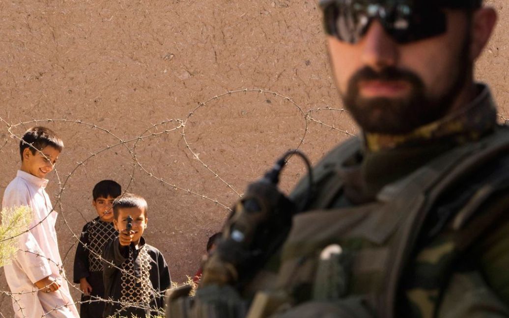 Афганський хлопчик направляє іграшковий пістолет на італійського солдата НАТО у в&#039;язниці Герат. (REUTERS / Raheb Homavandi) / © The Boston Globe