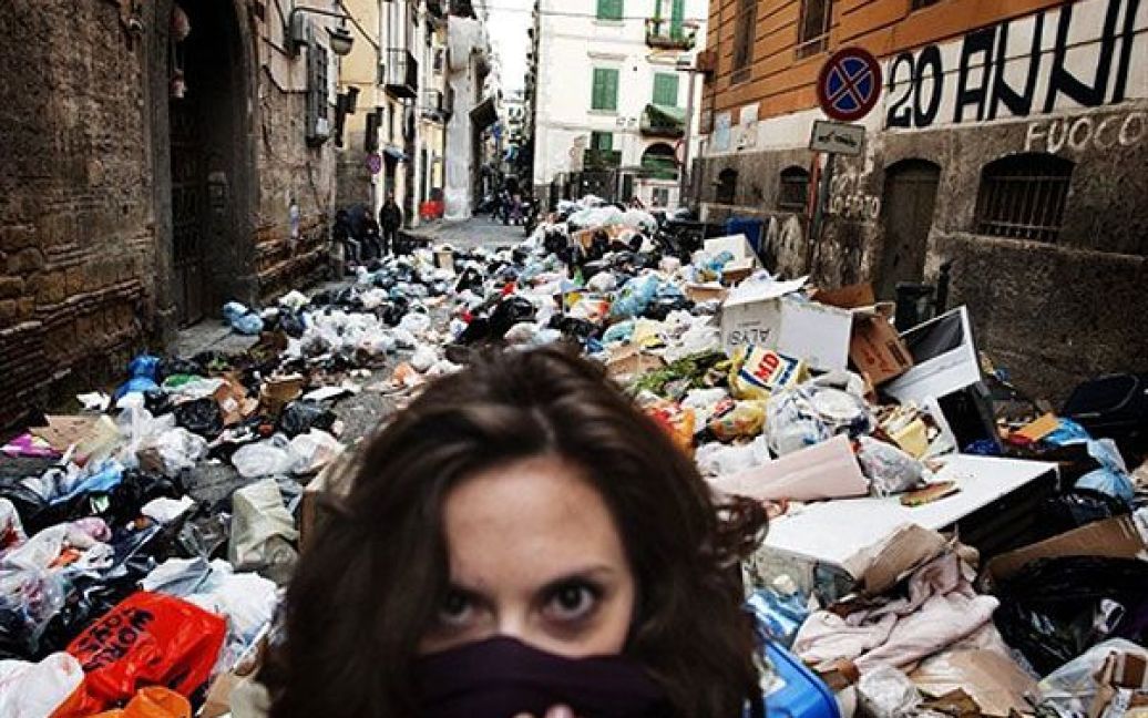 Італія, Неаполь. Жінка прикриває обличчя, доки вона йде вулицею, заваленою незібраним сміттям, у історичному районі міста Неаполь. Смердючі купи сміття накопичуються на вулицях Неаполя, наразі загальний обсяг незібраних відходів у місті досягає 3600 тонн. / © AFP