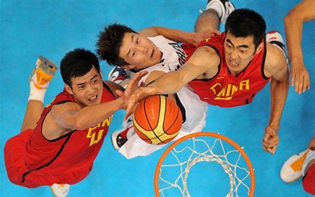 Китай, Гуанчжоу. Китайські баскетболісти Дін Чінгуй і Чжан Чжаосюй, а також спортсмен зі збірної Південної Кореї О Секуен ведуть боротьбу під кільцем під час матчу за золоту медаль на Азіатських іграх. / © AFP