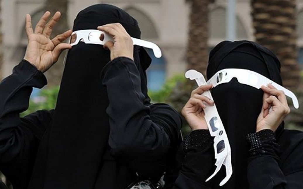Саудівська Аравія, Джидда. Саудівські жінки у чадрах тримають спеціальні темні окуляри, щоб побачити перше у 2011 році часткове сонячне затемнення, місто Джидда на Червоному морі. / © AFP