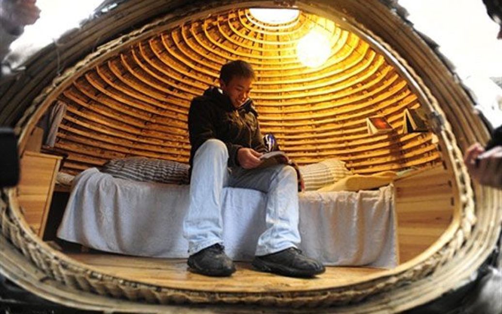 Китай, Пекін. 24-річний Дай Хайфей з китайської провінції Хунань лежить у своєму яйцеподібному мобільному будинку, в якому він мешкає упродовж останніх двох місяців неподалік від свого офісу в Пекіні. Сконструювати подібний будинок самостійно коштує близько 1000 доларів США. Він зроблений зі смуг бамбука і матраца, вкритого шаром водостійкого матеріалу, який також зберігає тепло. Назовні будинок вкрито мішками з тирсою і насінням трави, яка проростатиме навесні. / © AFP