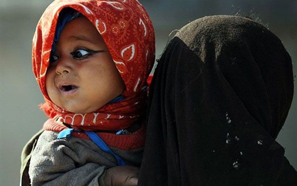 Афганістан, Гамсер. Афганська дівчинка тримає на руках свою молодшу сестру. / © AFP