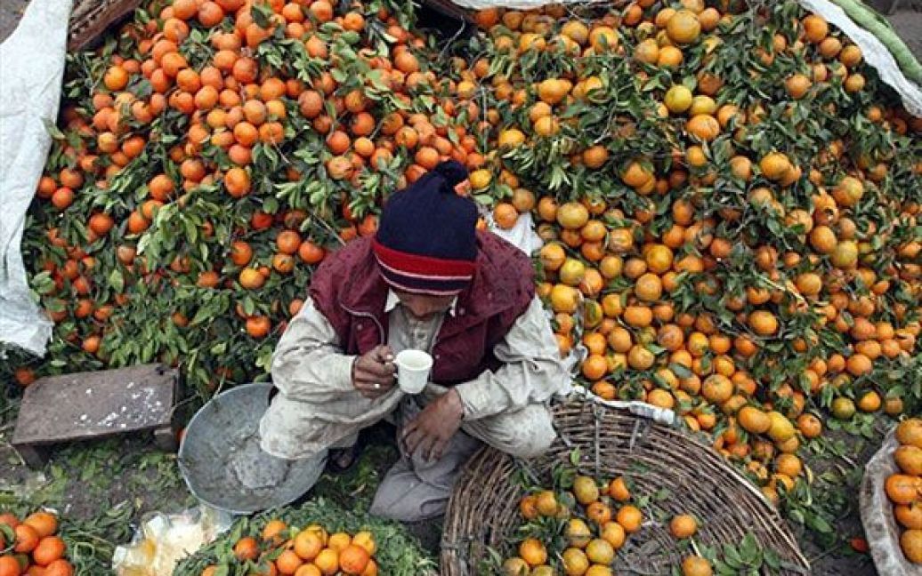 Пакистан, Лахор. Пакистанець п&#039;є чай і продає помаранчі на фруктовому ринку у Лахорі. / © AFP