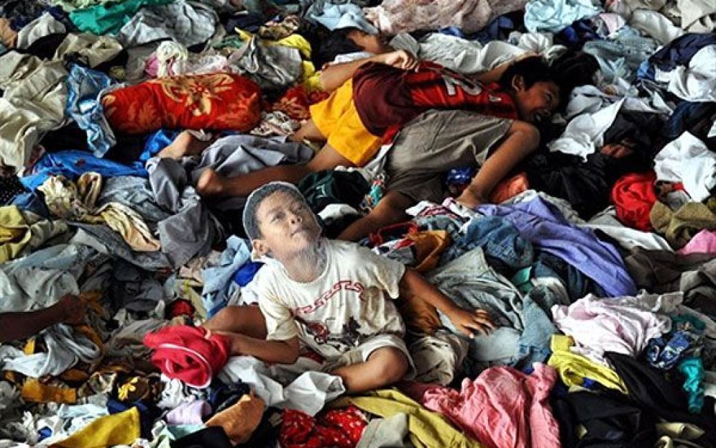 Індонезія, Слеман. Діти грають на купі одягу з гуманітарної допомоги, який привезли до табору людей, переміщених всередині країни через виверження вулкана Мерапі в Індонезії. В результаті виверження, в Індонезії загинули більше 200 людей, більше 380 тисяч людей були переміщені до тимчасових таборів. / © AFP