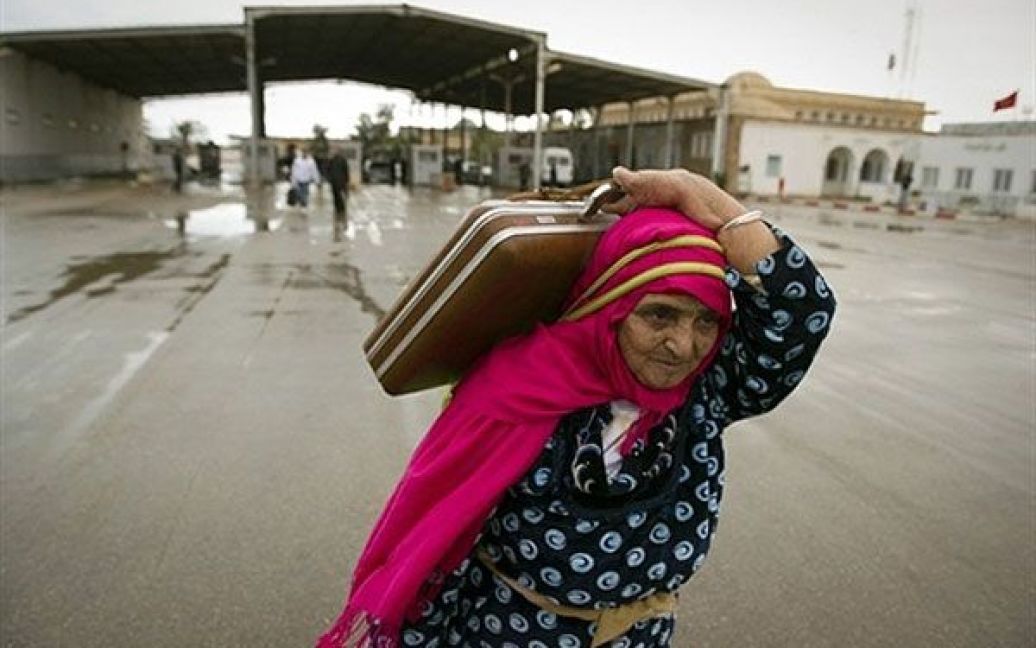 Туніс, Бен Гардана. Жінка несе сумки через прикордонний пост Ras Jdir між Лівією і Тунісом. Cотні мешканців Тунісу почали тікати з Лівії, щоб уникнути хвилювань. Уряд Тунісу звернувся до Лівії з вимогами припинити використання сили проти цивільних осіб у кривавому придушенні протестів. / © AFP