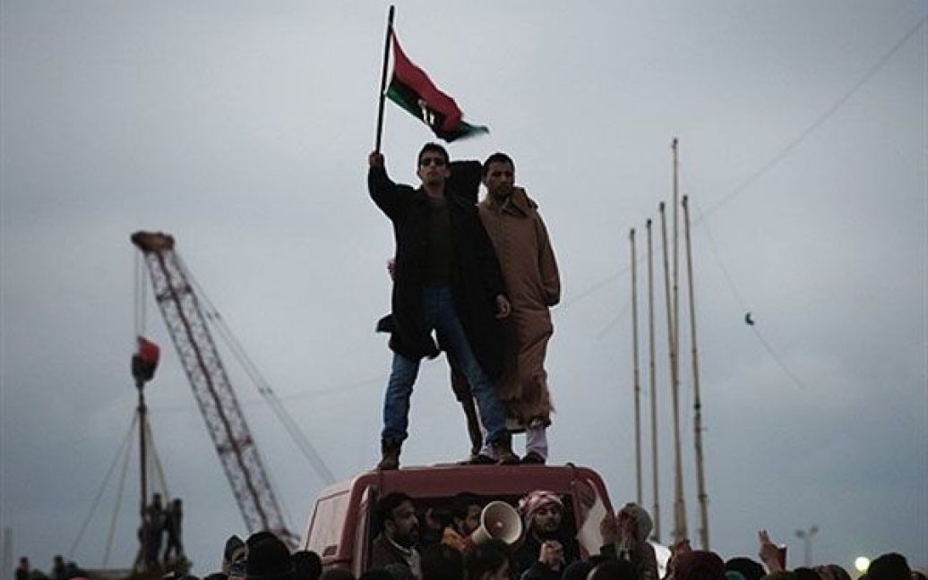 Лівійська Арабська Джамахірія, Бенгазі. Лівієць розмахує національним прапором під час акції перед будівлею суду в місті Бенгазі. В країні зберігається політична нестабільність, і трвають повстання проти режиму Муамара Каддафі. / © AFP