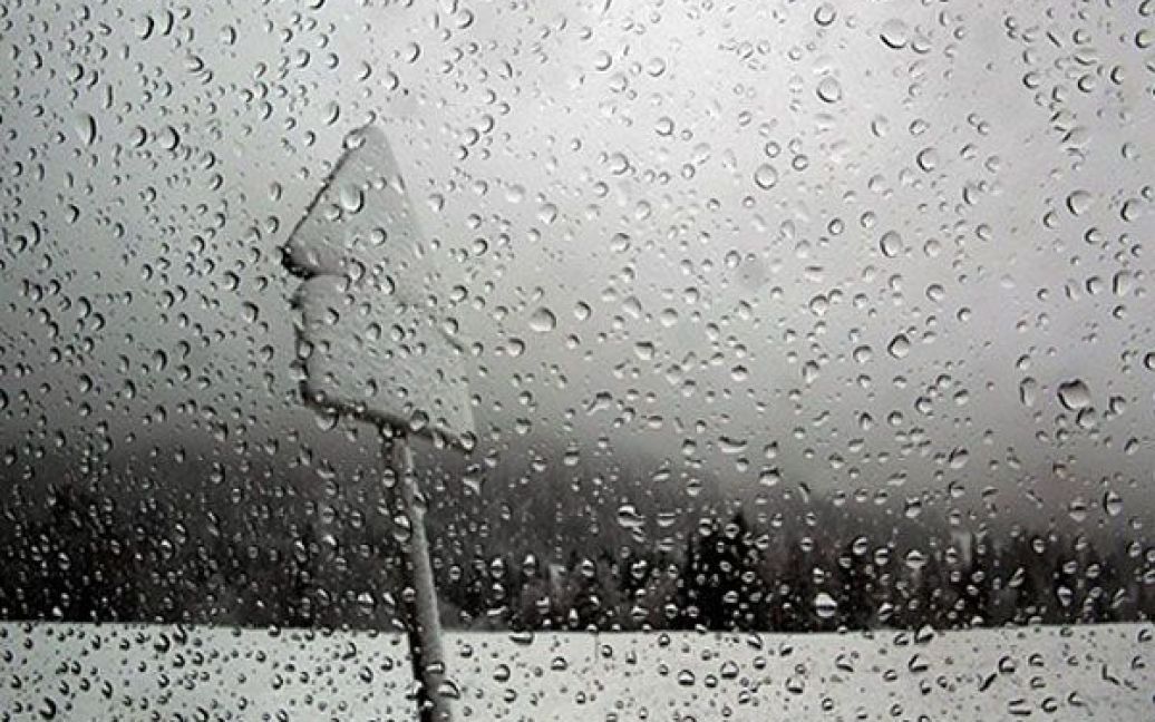 Німеччина. Дорожній знак, вкритий снігом, видно крізь дощ поруч із німецько-австрійським кордоном у містечку Бальдершванг. Метеорологи прогнозують баварцям прохолодну і дощову погоду на найближчі дні. / © AFP