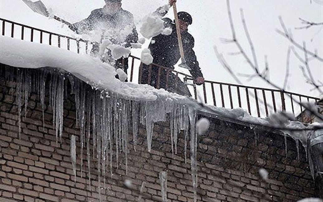 Білорусь, Мінськ. Муніципальні працівники збивають з даху однієї з будівель у Мінську небезпечні бурульки. / © AFP