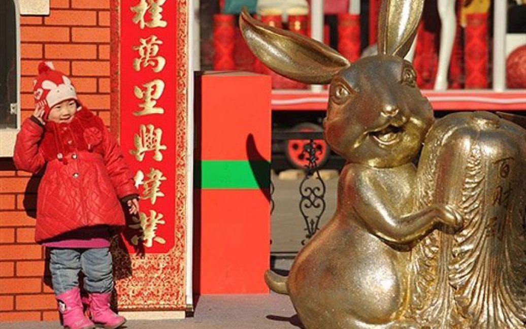 Китай, Пекін. Дівчинка позує поруч із новорічним кроликом перед торговельним центром у Пекіні. / © AFP