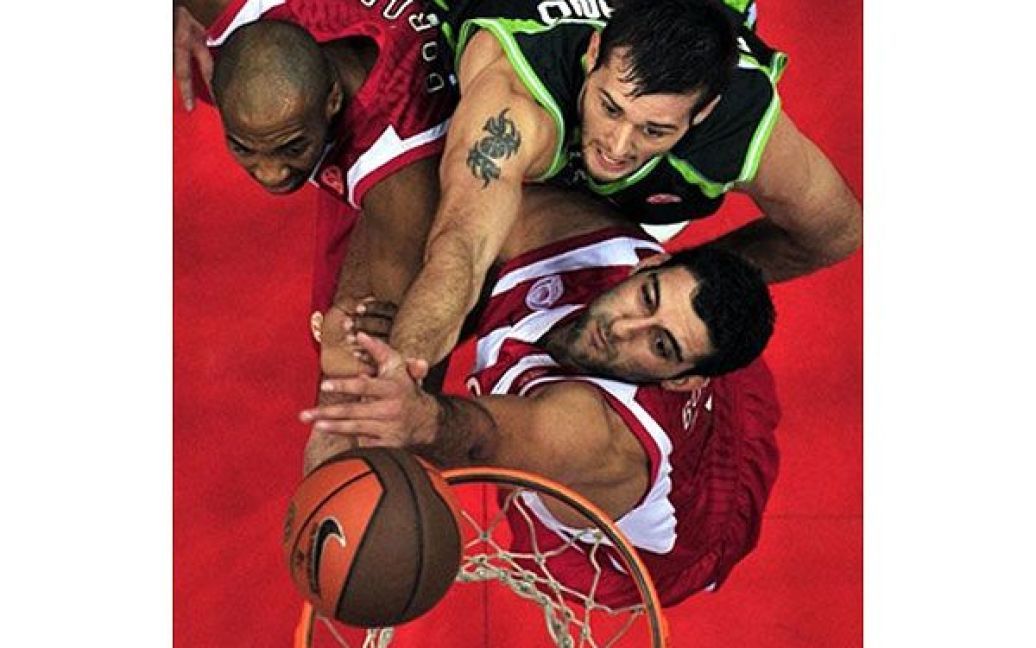 Греція, Афіни. Джоел Фріленд ("Unicaja") стрибає, щоб закинути м&rsquo;яч у кільце, перед гравцями "Olympiakos" під час баскетбольного матчу Євроліги у Афінах. / © AFP