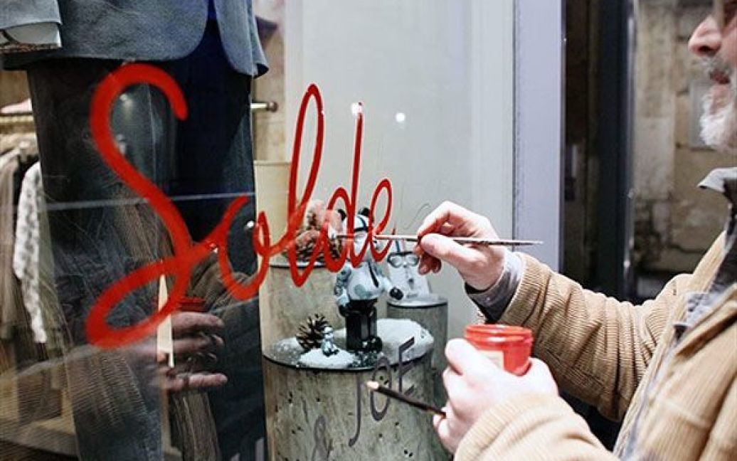Франція, Париж. Людина малює слово "Soldes" ("Розпродаж") на вітрині магазину у Парижі напередодні першого дня розпродажів. / © AFP