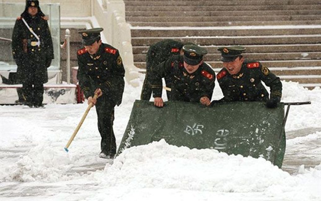 Китай, Пекін. Китайські військові прибирають сніг на площі Тяньаньмень у Пекіні. Вперше за 60 років у Пекіні перший снігопад затримався на кілька місяців. Останніми опадами, які пройшли до першого снігу у Пекіні, були дощі 25 жовтня 2010 року. / © AFP