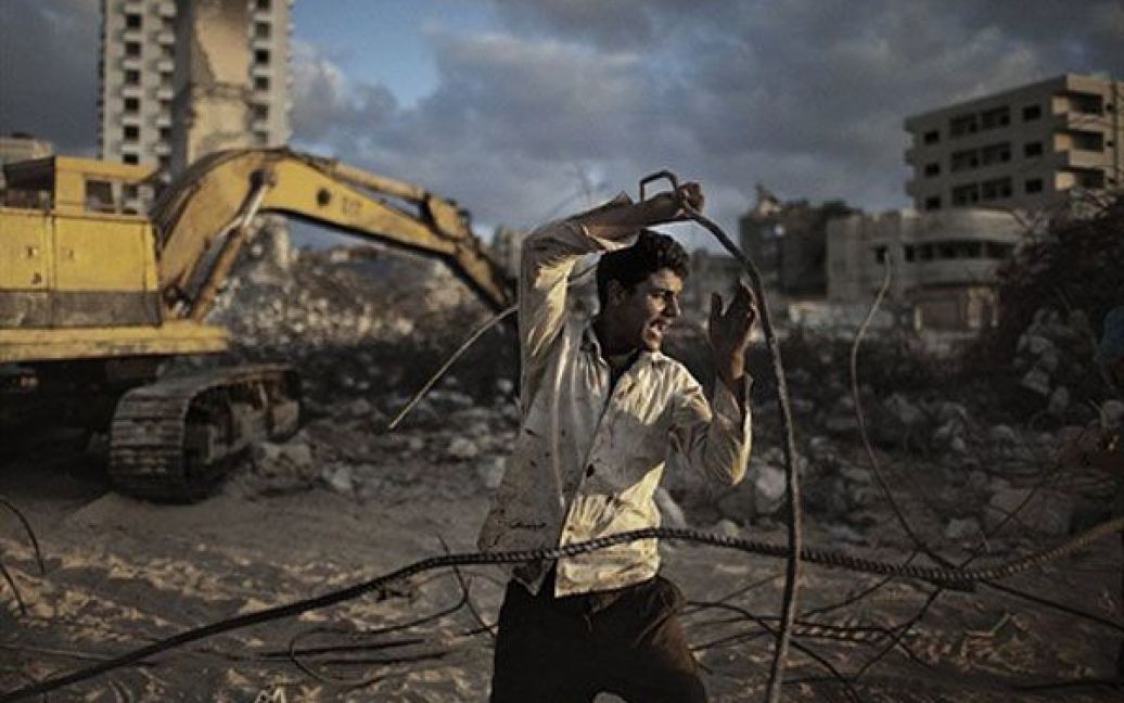 Місто Газа. Палестинець збирає металобрухт з уламків готелю на набережній міста Гази. Будівлі, пошкоджені під час останніх безладів, стали джерелом будівельних матеріалів для місцевого населення. / © AFP