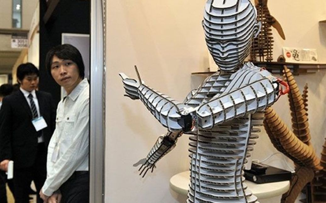 Японія, Токіо. Художниця Акі, яка працює з картонними витворами мистецтва, показує манекена-робота "Dropop", зробленого з картону із вісьмома приводами, які переміщують голову і руки робота. Картонного роота презентували на Токійській міжнародній виставці подарунків. / © AFP