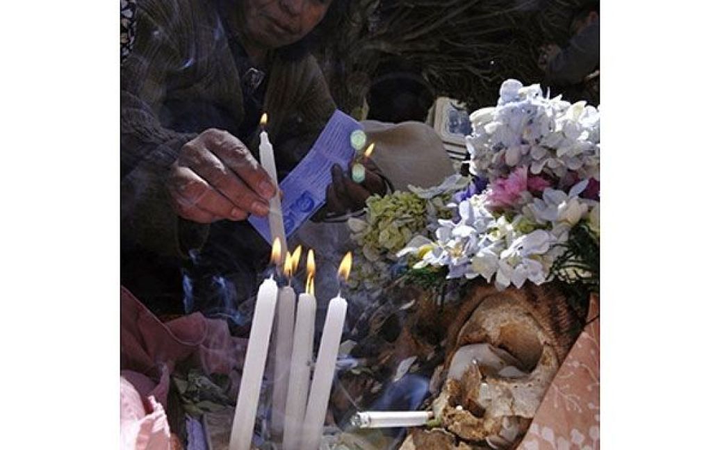 Болівія, Ла-Пас. Жінка запалює свічки перед черепом &Ntilde;atitas на громадському кладовищі у місті Ла-Пас під час святкування Дня Черепа. / © AFP
