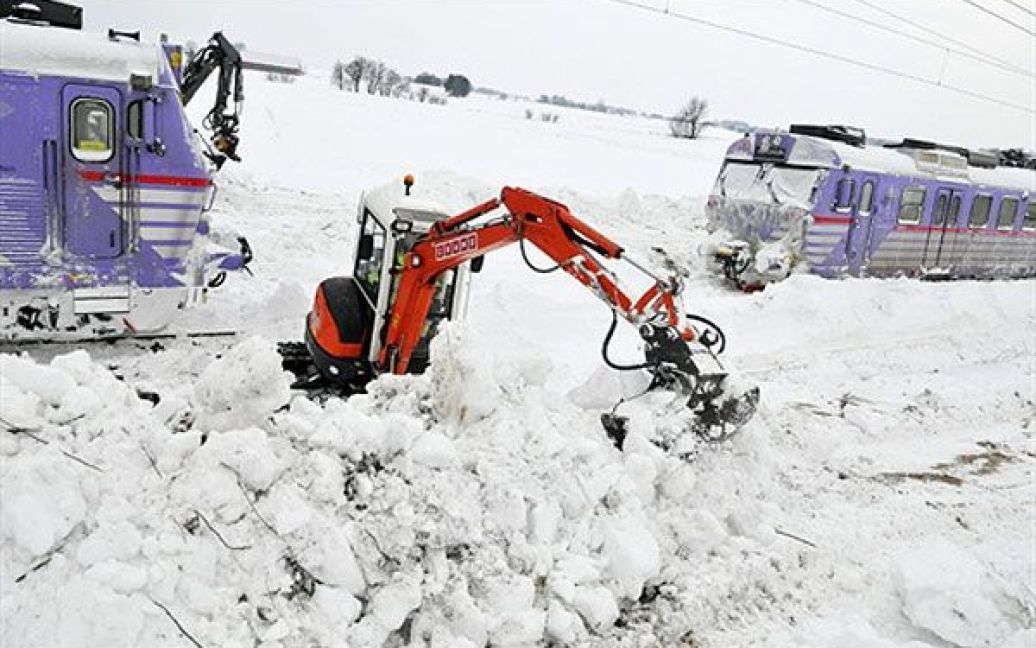 Швеція, Балкакра. Люди прибирають сніг за допомогою екскаваторів з рейок, на яких снігопад заблокував два місцевих поїзди на півдні Швеції. / © AFP