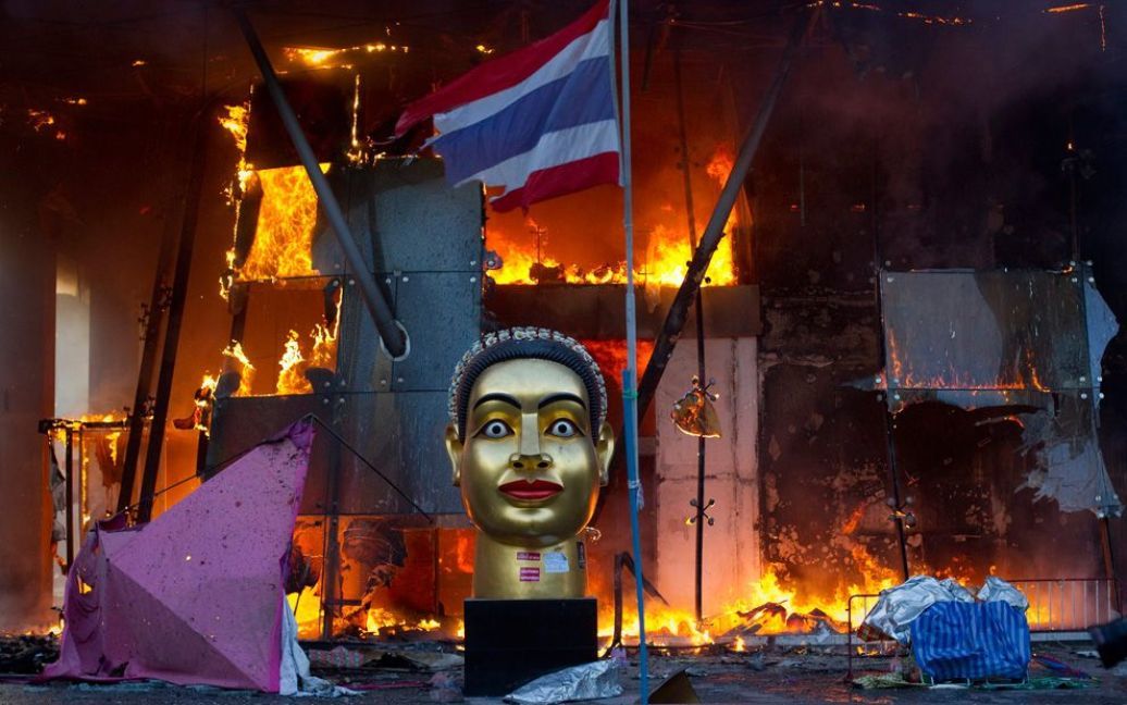 Статуя і розірваний тайський прапор перед палаючим торговим центром у Бангкоку під час зіткнень солдатів і активістів опозиційного руху "червоних сорочок". (REUTERS / Adrees Latif) / © The Boston Globe