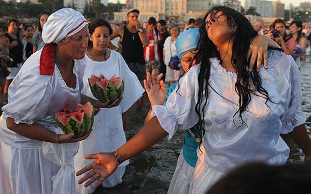 Уругвай, Монтевідео. Жінки беруть участь у ритуалі на честь богині Жанаїни, богині моря за афро-американською релігією Умбанда, на пляжі Рамірес у Монтевідео. Тисячі віруючих зібрались на пляжі уругвайської столиці, щоб принести подарунки богині. / © AFP