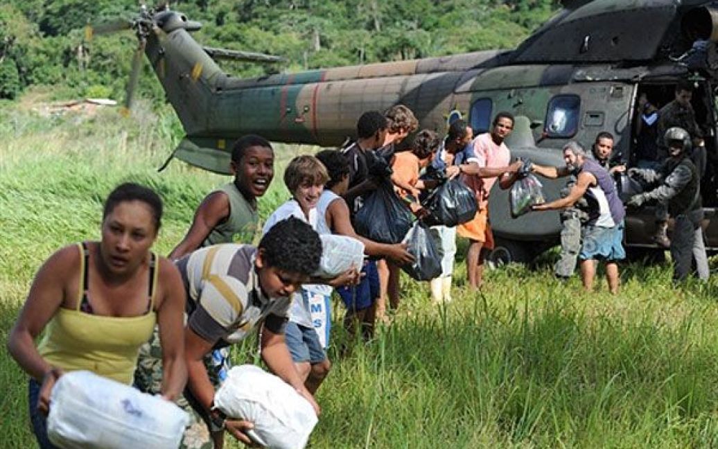 Бразилія, Сан-Бенто. Місцеві жителі, які постраждали від руйнівної повені і були ізольовані у місті Сан-Бенто, штат Ріо-де-Жанейро, отримують гуманітарну допомогу. 
В результаті найгіршої повені за останні десятиліття, у Бразилії загинули щонайменше 744 людини. / © AFP