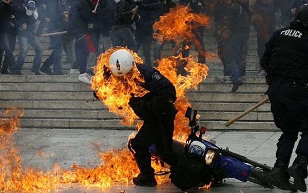 Греція, Афіни. Поліцейський, охоплений вогнем, намагається втекти після того, як демонстранти влучили у нього пляшкою із запальною сумішшю під час заворушень перед будівлею парламенту в Афінах. У Греції почався новий загальнонаціональний страйк. / © AFP
