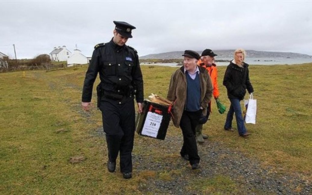Ірландія, Інішфрі. Ірландський поліцейський та голова виборчої комісії несуть урну з бюлетенями. В Ірландії почалися загальні вибори. / © AFP
