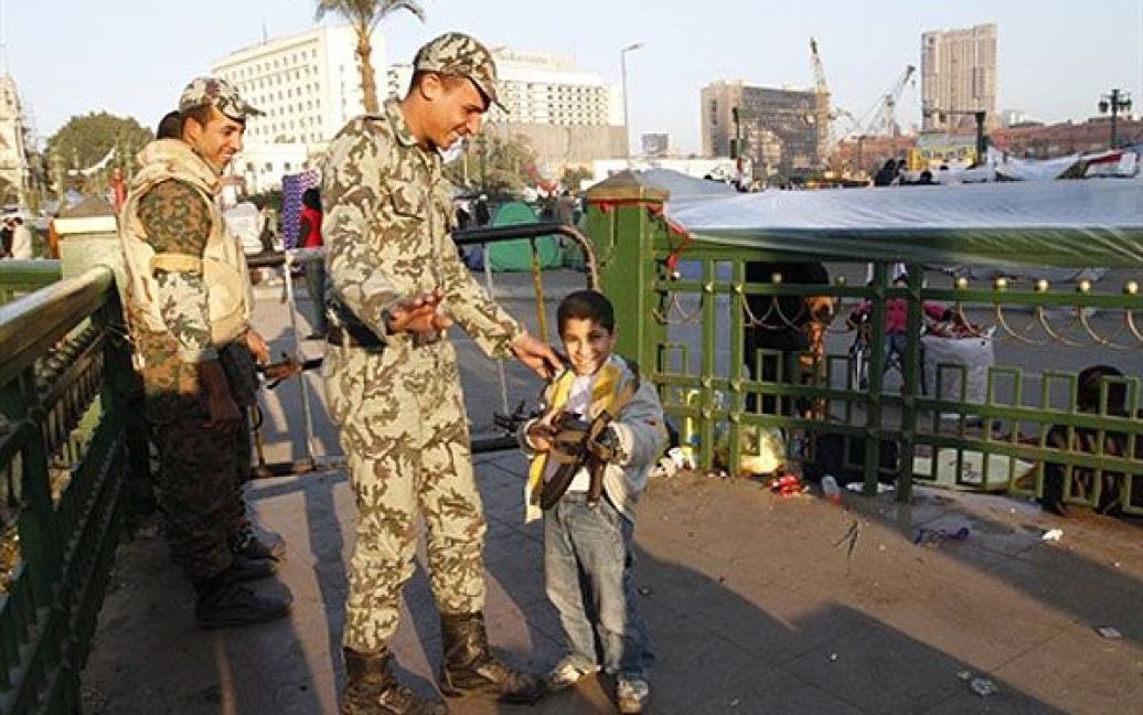 Єгипет, Каїр. Солдат дає дитині потримати зброю під час антиурядової акції протесту на площі Тахрір у Каїрі. / © AFP