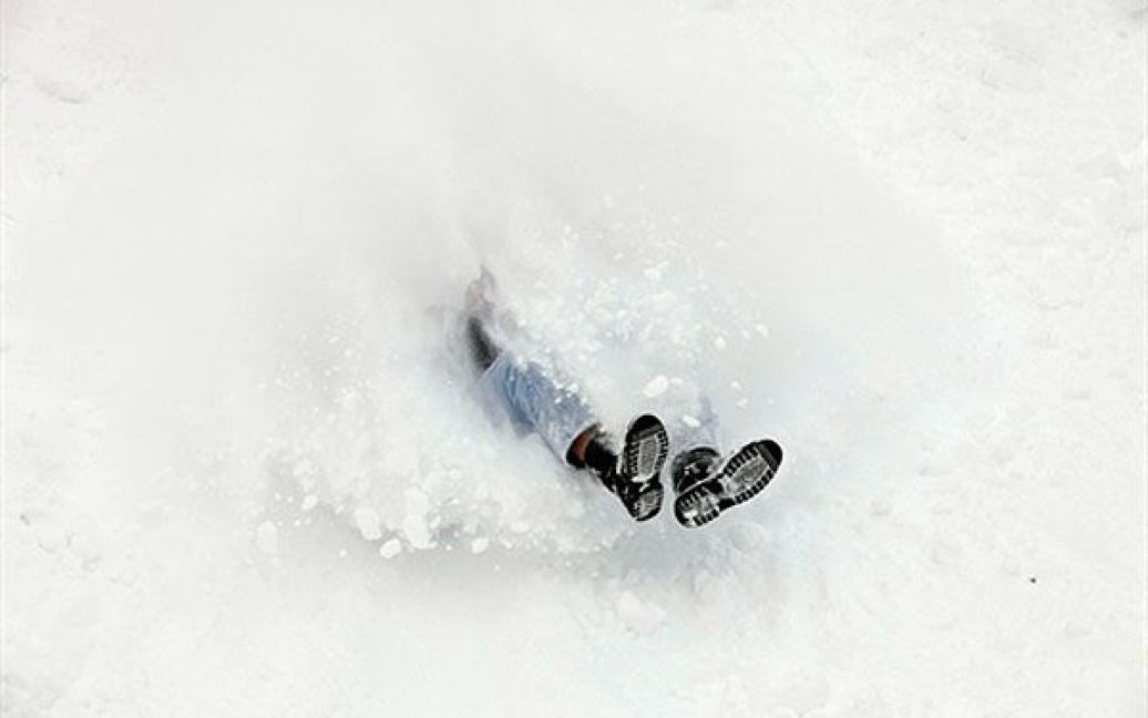 США, Айова-Сіті. Студент університету штату Айова катається на санках з пагорба позаду початкової школи імені Лінкольна в Айова-Сіті, штат Айова. У деяких районах Середнього Заходу США випало майже 40 см снігу. / © AFP